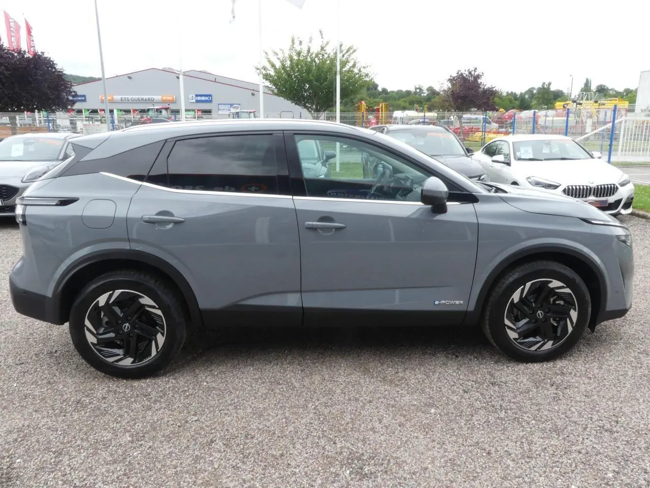 Profil côté gauche d'un Nissan Qashqai 1.5 e-Power gris métallisé avec jantes alliage 18 pouces et vitres teintées.