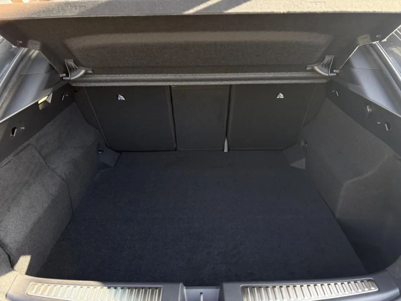 Coffre ouvert vu de l'arrière d'une Renault Rafale gris schiste, espace de chargement vide et tapis noir.