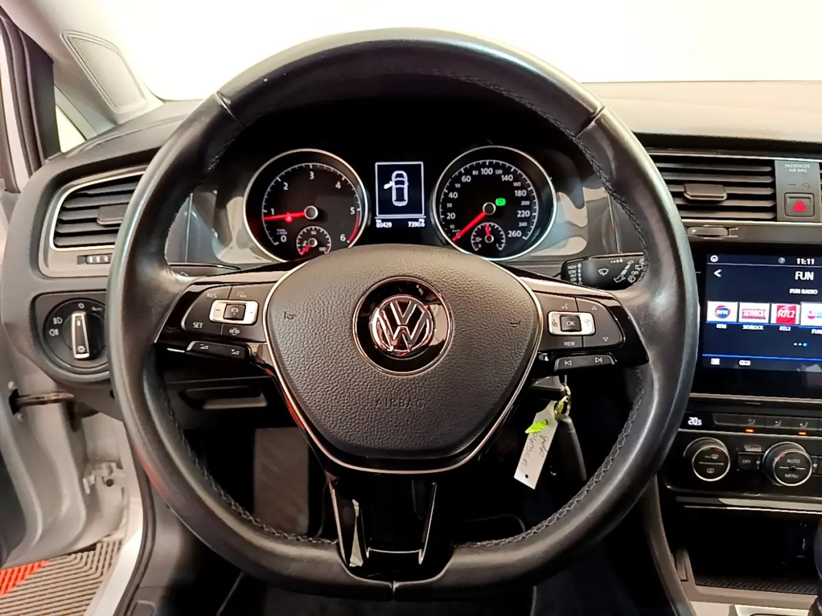 Vue rapprochée du volant cuir noir de la Volkswagen Golf 2019 avec tableau de bord et écran tactile allumé.