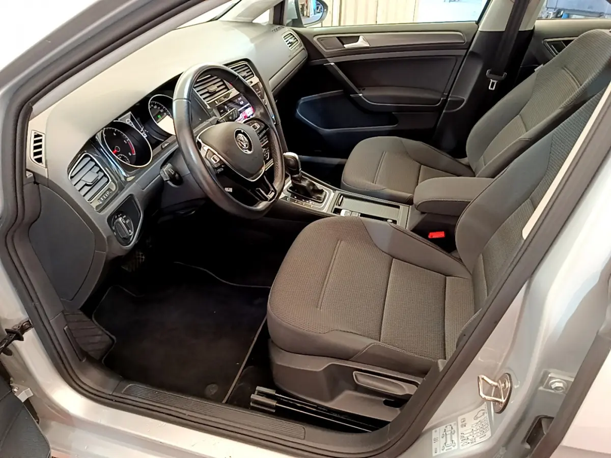 Intérieur de la Volkswagen Golf gris clair 2019, vue côté conducteur montrant sièges et tableau de bord avec volant cuir.