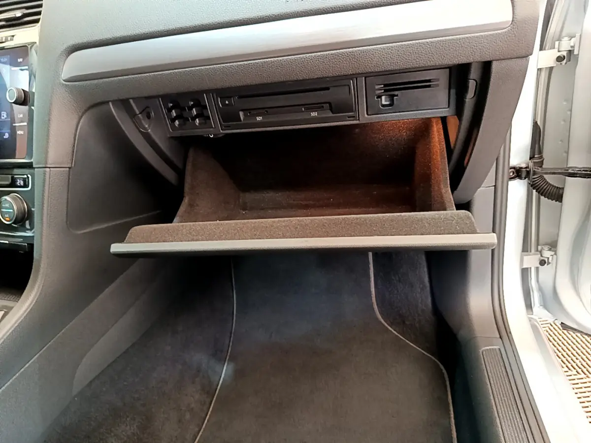 Gros plan sur la boîte à gants ouverte du Volkswagen Golf gris clair 2019, montrant les lecteurs SD et l'éclairage intérieur.