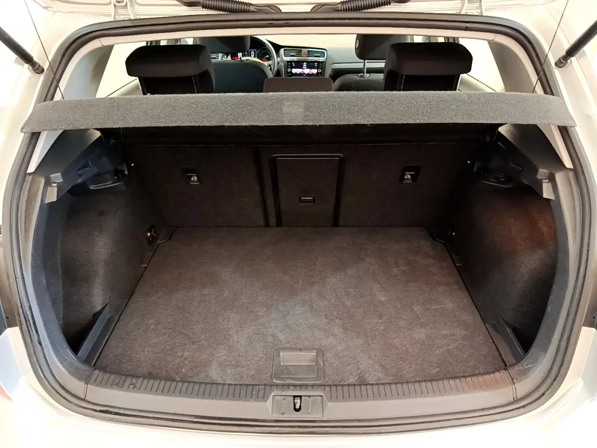 Coffre ouvert d'une Volkswagen Golf gris clair 2019, vue arrière montrant l'espace de chargement et la tablette arrière.