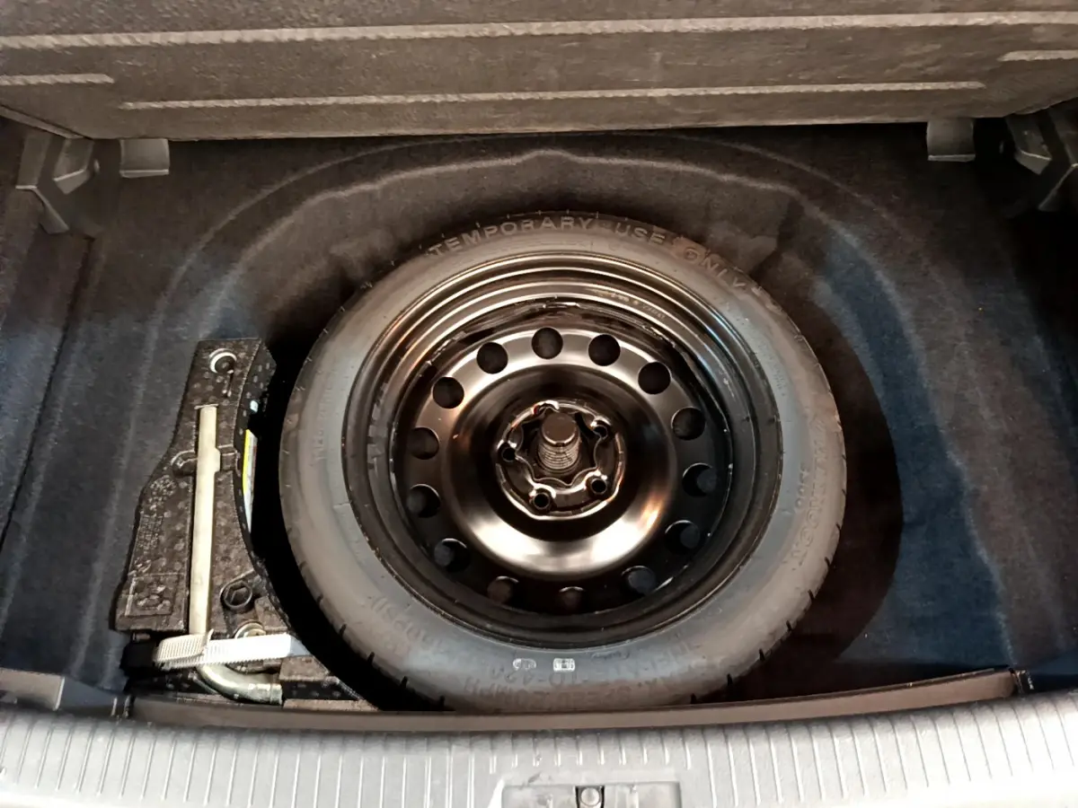 Roue de secours galette noire dans le coffre d'une Volkswagen Golf 1.6 TDI 2019 gris clair.