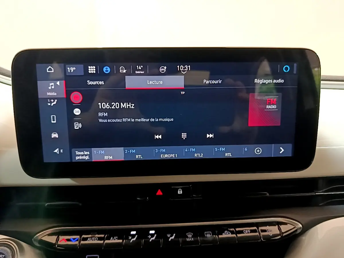 Écran tactile central affichant la radio FM dans l'habitacle blanc d'une Fiat 500 électrique Icône 2022.