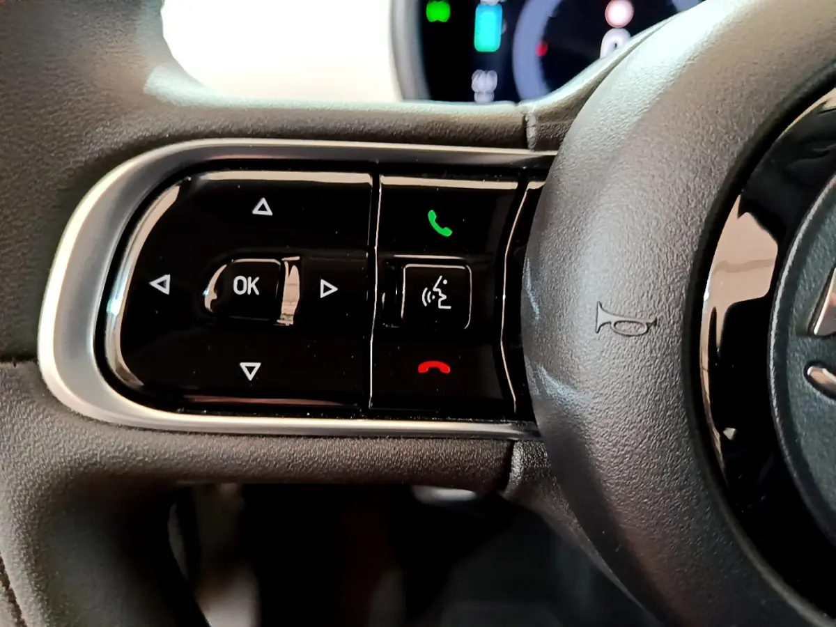 Gros plan sur les commandes gauche du volant noir de la Fiat 500 électrique blanche version 42kWh Icône 2022.