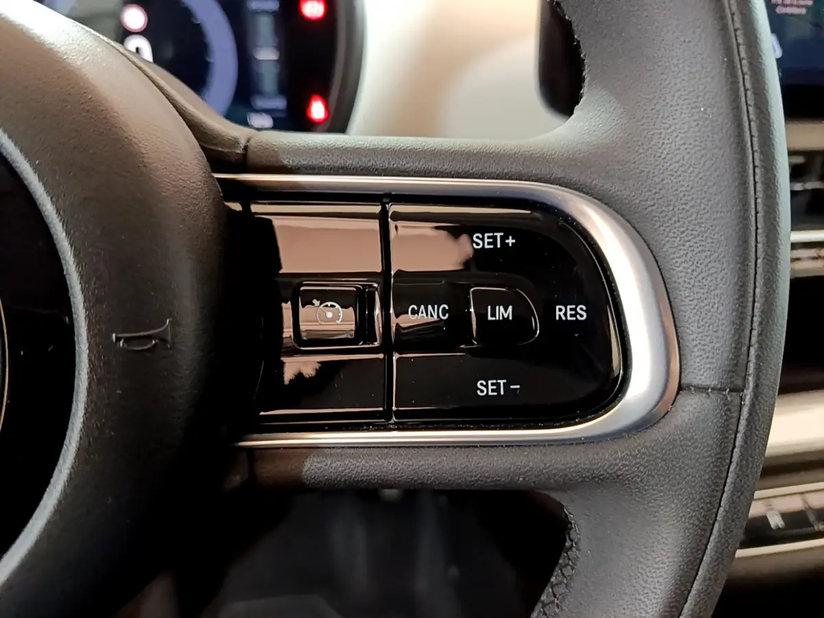 Gros plan sur les commandes du régulateur de vitesse au volant cuir noir d'une Fiat 500 blanche électrique 2022.