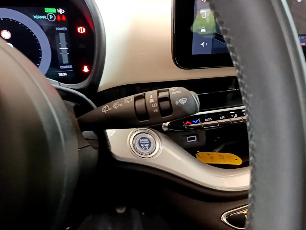 Détail intérieur du tableau de bord blanc de la Fiat 500 électrique 2022, avec bouton start/stop et commandes au volant visibles.