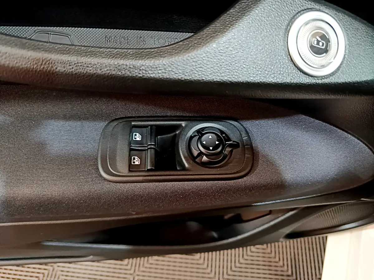 Détail des commandes de lève-vitres et rétroviseurs sur la porte côté gauche d'une Fiat 500 blanche Icône 2022 électrique.