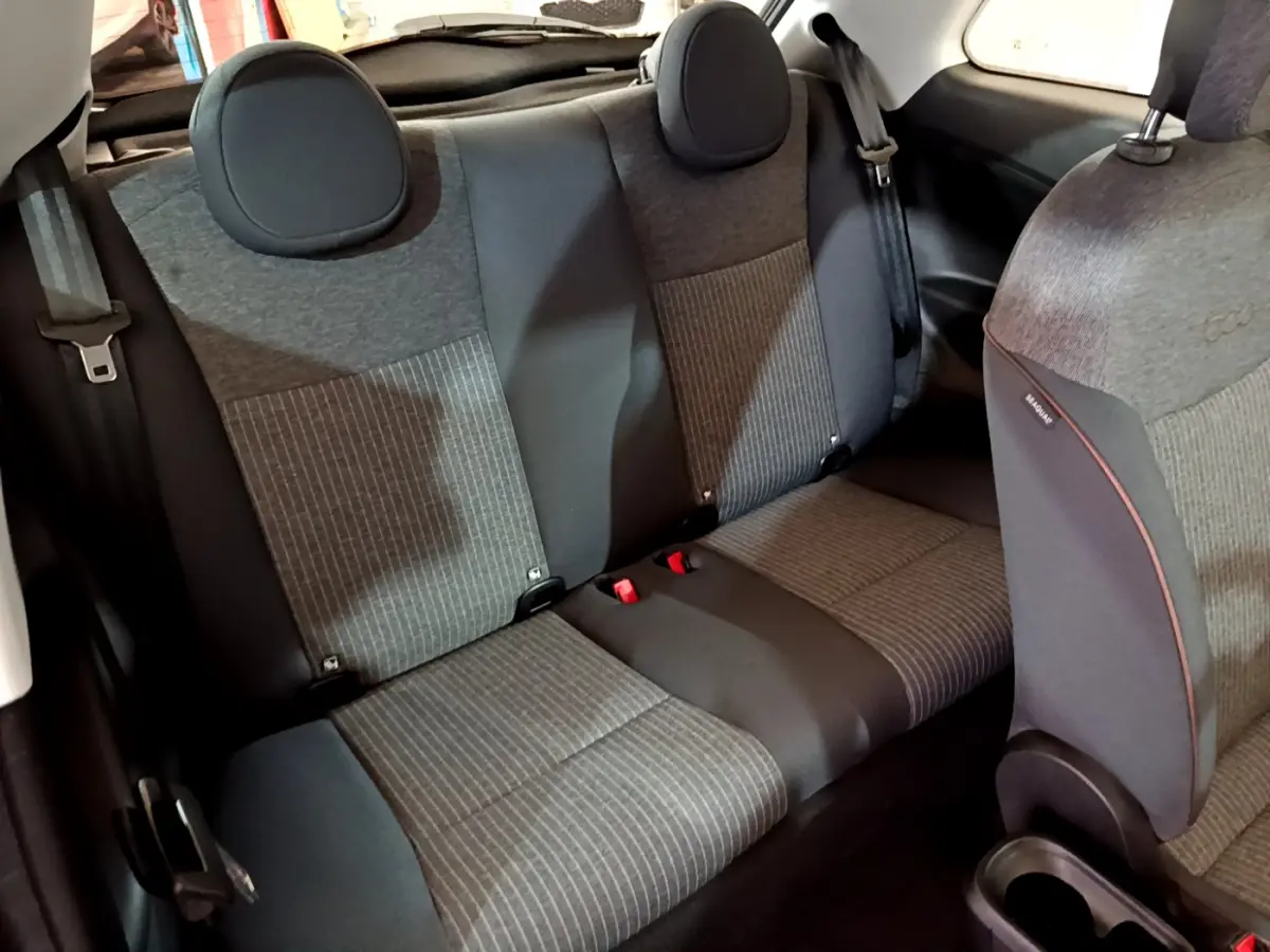 Vue intérieure arrière des sièges gris foncé et noir de la Fiat 500 42kWh Icône électrique 2022 avec appuie-têtes ronds.