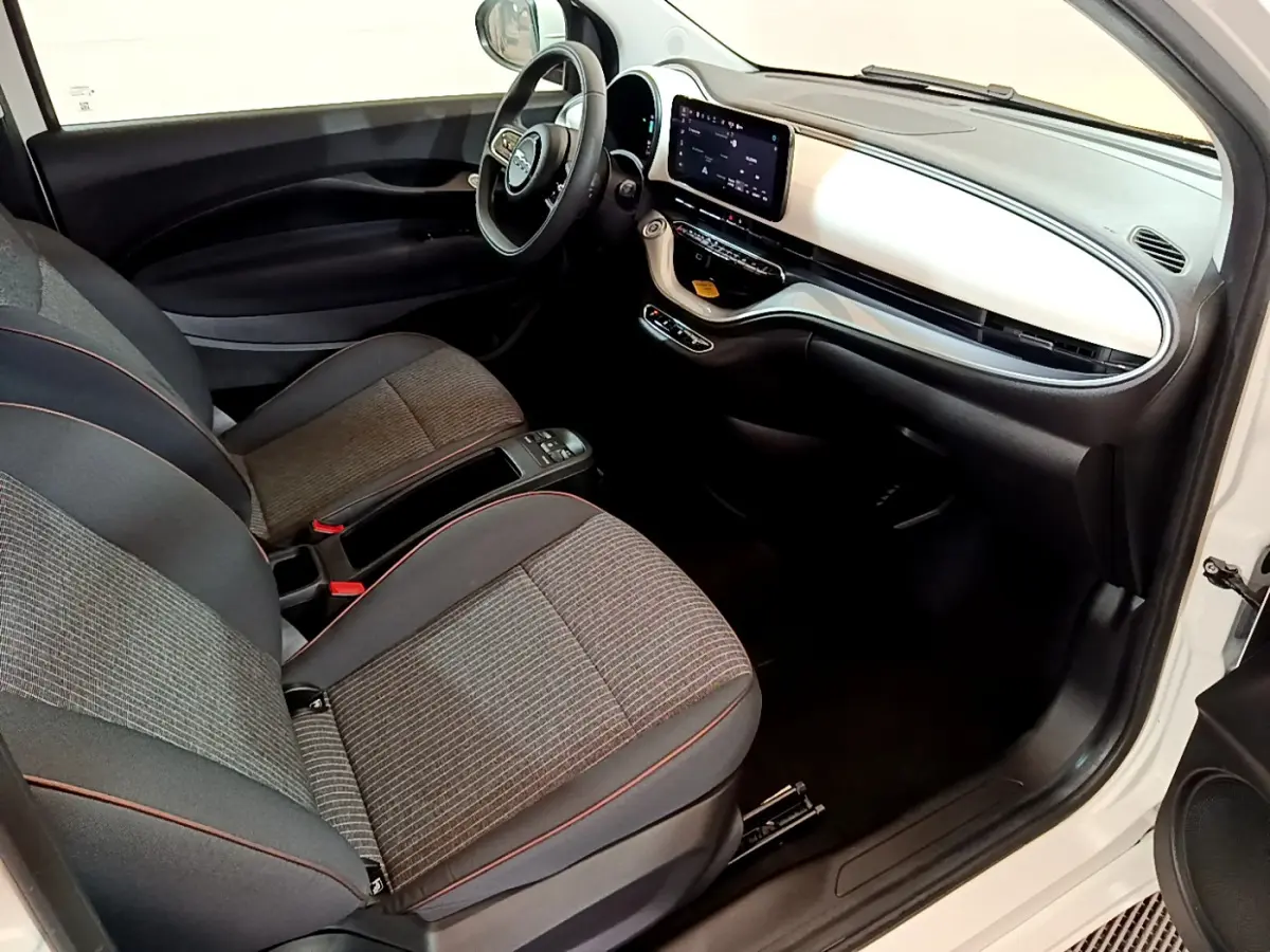 Intérieur avant droit de la Fiat 500 Icône 42kWh 2022 blanc, tableau de bord blanc et sièges gris à surpiqûres rouges