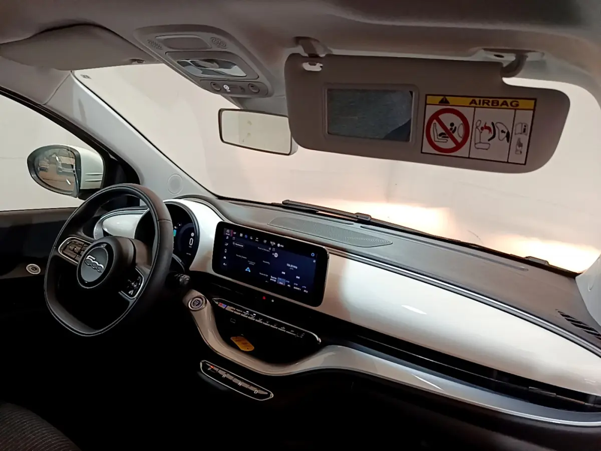 Intérieur avant droit de la Fiat 500 électrique blanche 2022, tableau de bord blanc brillant avec écran tactile central.