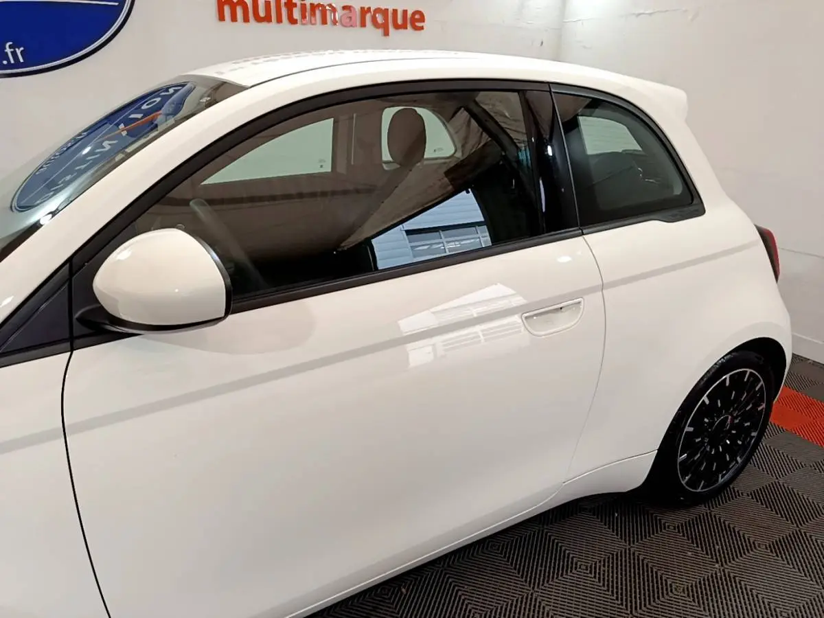 Profil côté gauche d'une Fiat 500 électrique blanche, mettant en valeur sa silhouette compacte et ses jantes noires design.