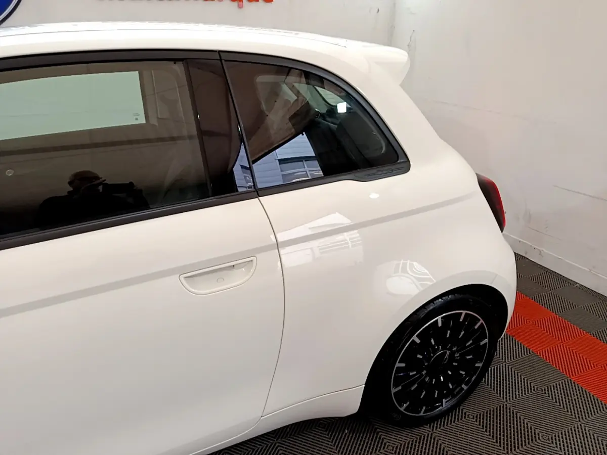 Vue côté droit arrière d'une FIAT 500 électrique blanche 42kWh Icône avec jante noire et logo 500 sur montant arrière.