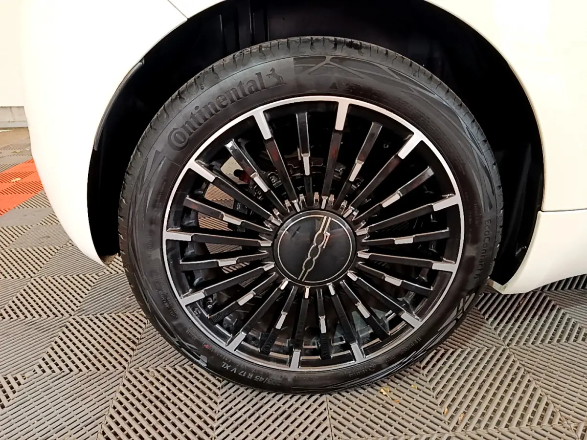 Gros plan sur la jante noire et argentée de la roue avant droite d'une FIAT 500 blanche électrique 2022 Icône.