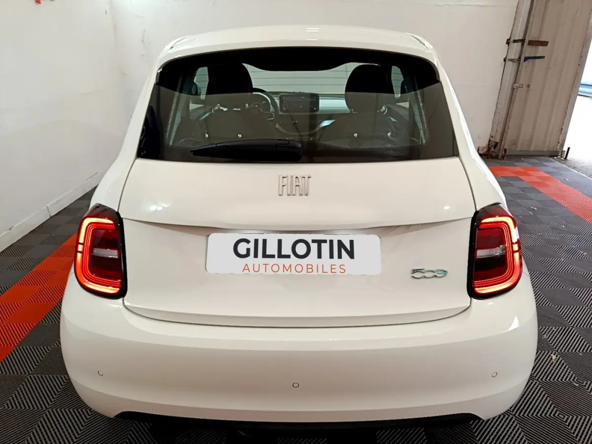Vue arrière d'une FIAT 500 blanche avec feux LED allumés dans un garage fermé.