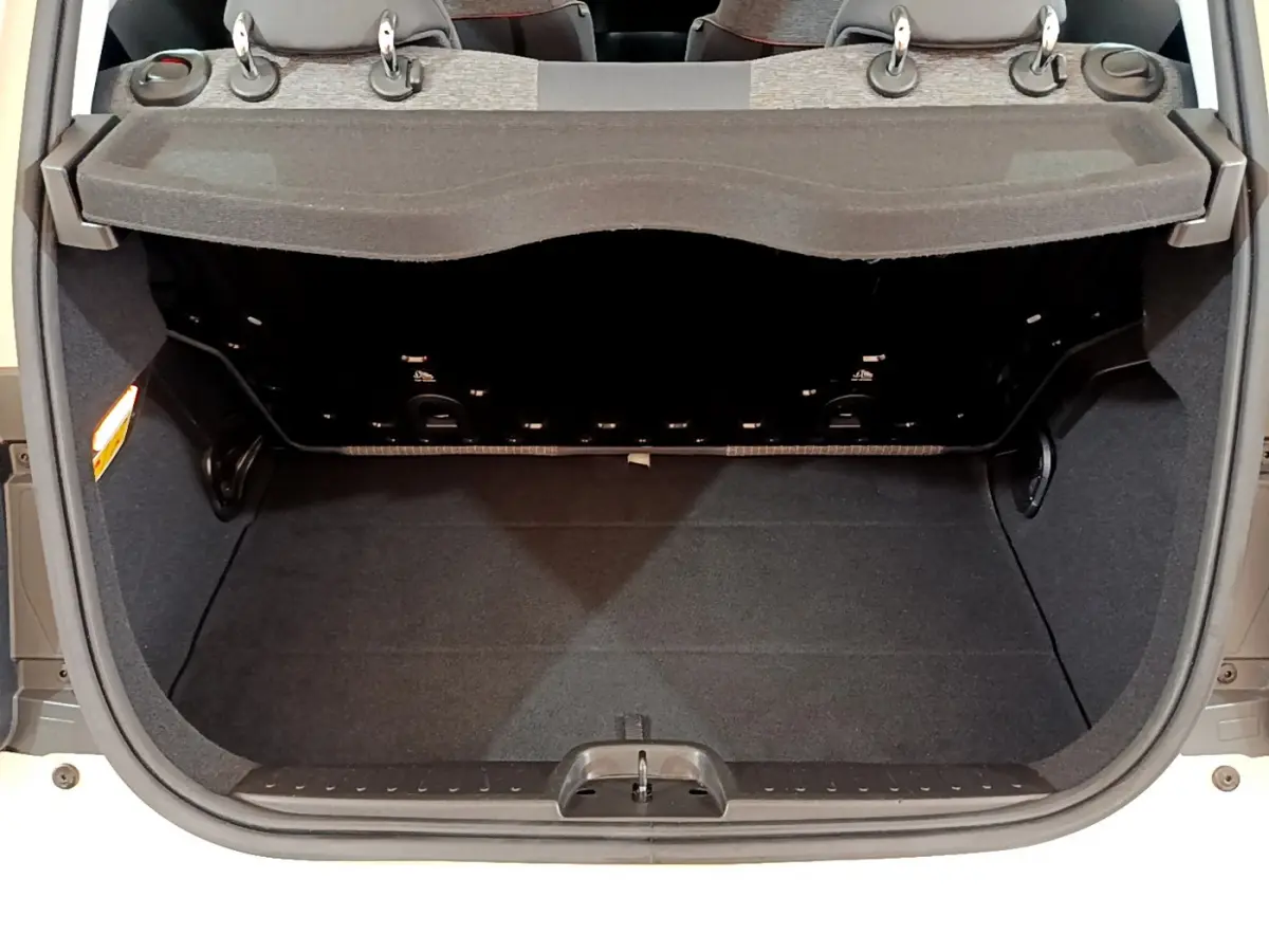 Coffre ouvert vu de l'arrière d'une FIAT 500 blanche électrique, montrant l'espace de chargement et la tablette de séparation.