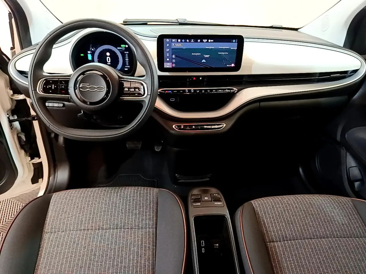 Vue intérieure avant de la FIAT 500 électrique blanche 2022, tableau de bord épuré avec écran tactile central et volant multifonctions.