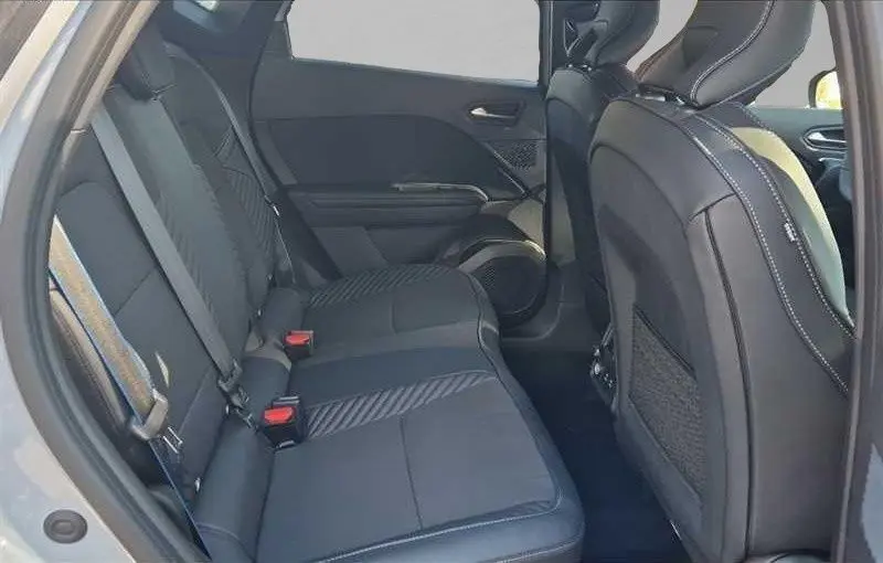 Vue intérieure arrière côté gauche du Renault Captur E-Tech hybride 2025, sièges noirs avec surpiqûres blanches.