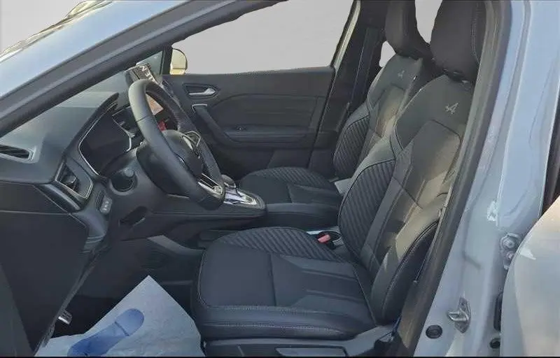 Vue intérieure côté conducteur du Renault Captur E-Tech hybride 2025, sièges noirs avec logo Alpine brodé sur appuie-tête.