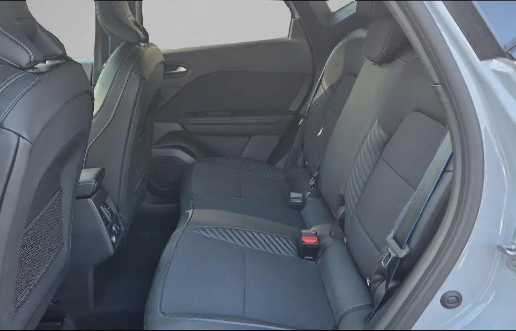 Vue intérieure arrière droite du Renault Captur E-Tech hybride 2025 avec sièges en tissu noir et ceinture grise.