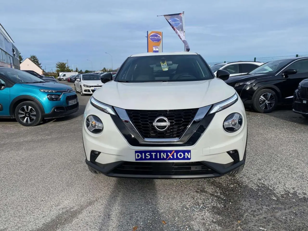 Vue frontale d'un Nissan Juke blanc perle 2024 avec calandre noire et logo Nissan bien visible.