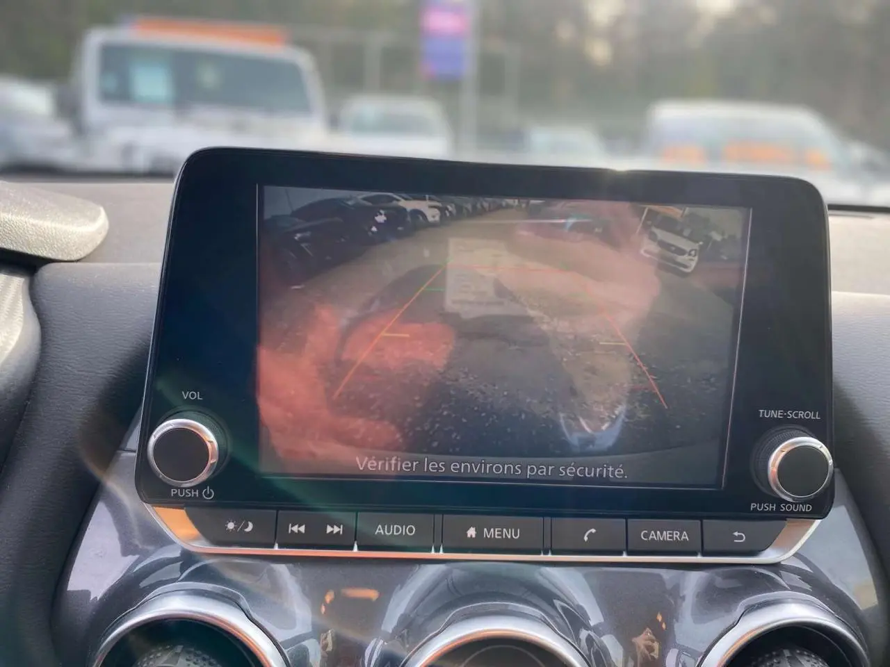 Écran central du Nissan Juke blanc perle 2024 montrant l'image de la caméra de recul avec les lignes de guidage.