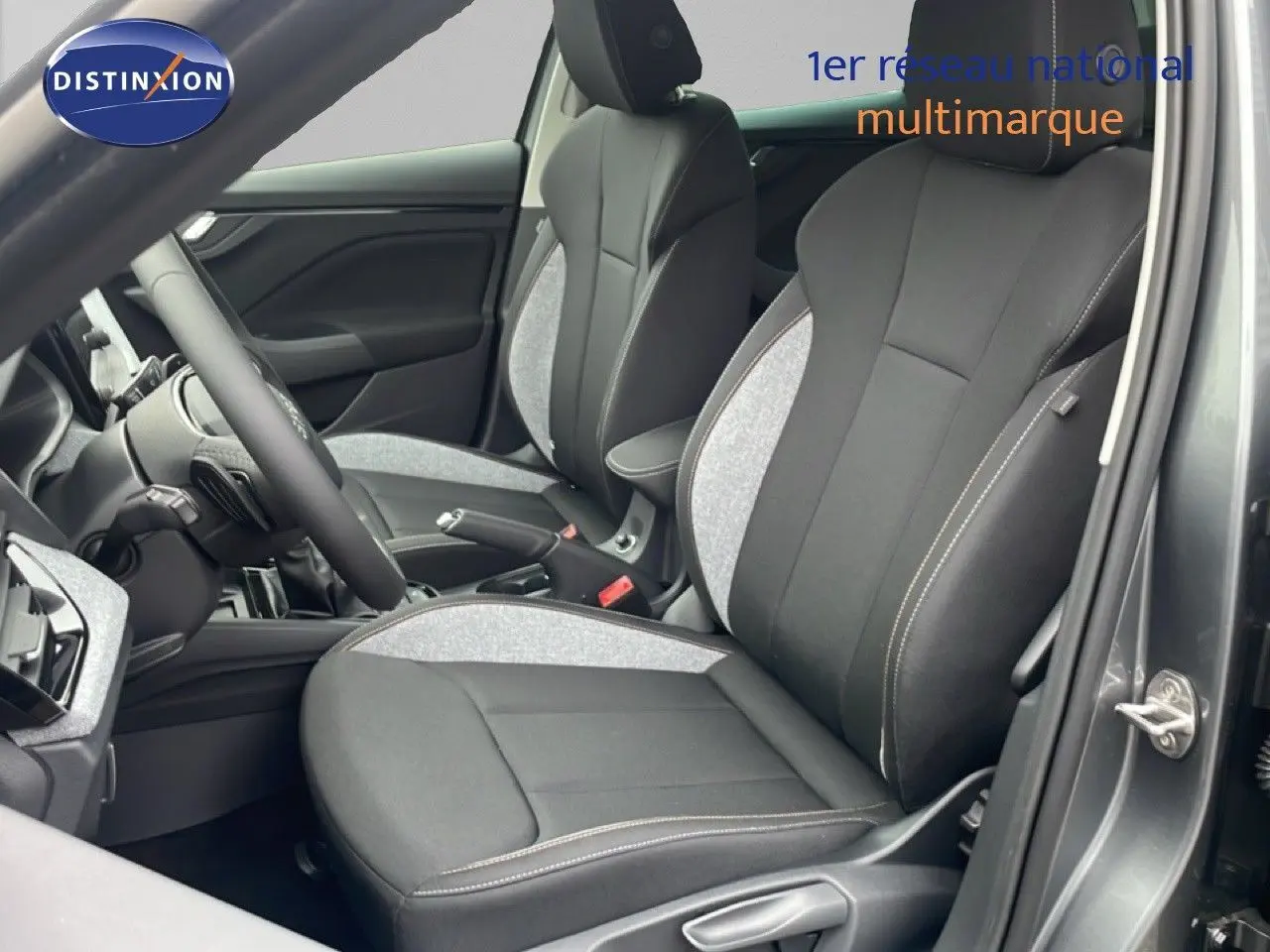 Vue intérieure côté conducteur du Skoda Kamiq 2025 avec sièges tissu noir et gris graphite, volant et tableau de bord visibles.
