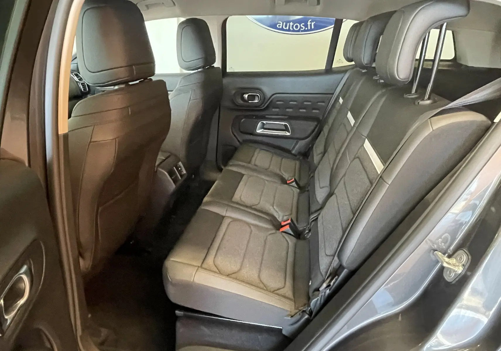 Vue intérieure côté droit des sièges arrière en tissu gris du Citroën C5 Aircross hybride 2025, avec portes ouvertes.