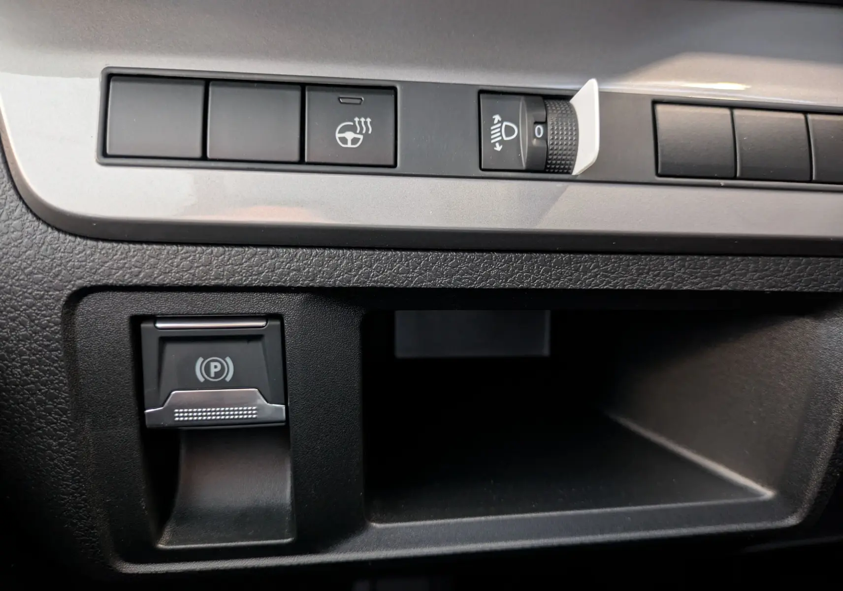 Gros plan sur les commandes noires du tableau de bord du Peugeot Traveller 2.2 180 EAT8 XL Business, avec bouton de frein à main électrique.