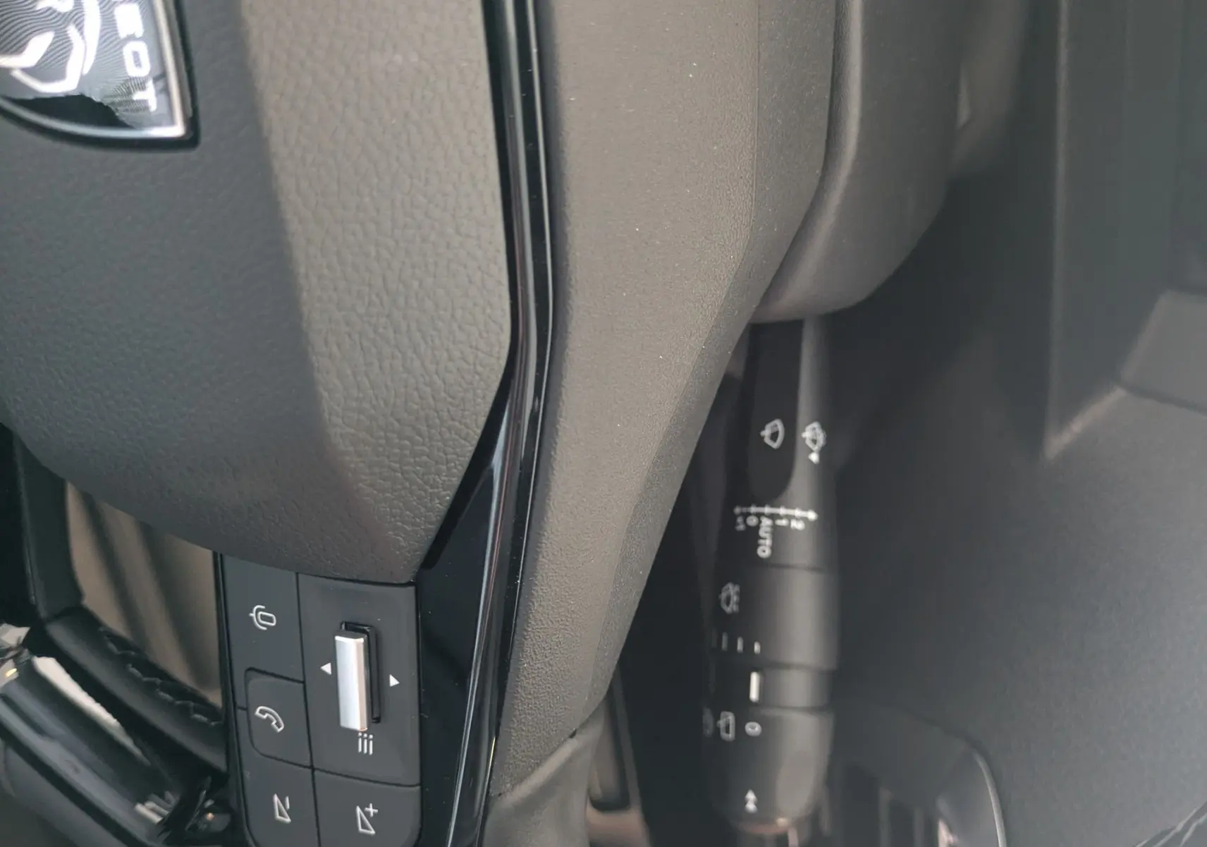 Détail du volant noir de Peugeot Traveller 2026 avec commandes intégrées et logo lion visible.