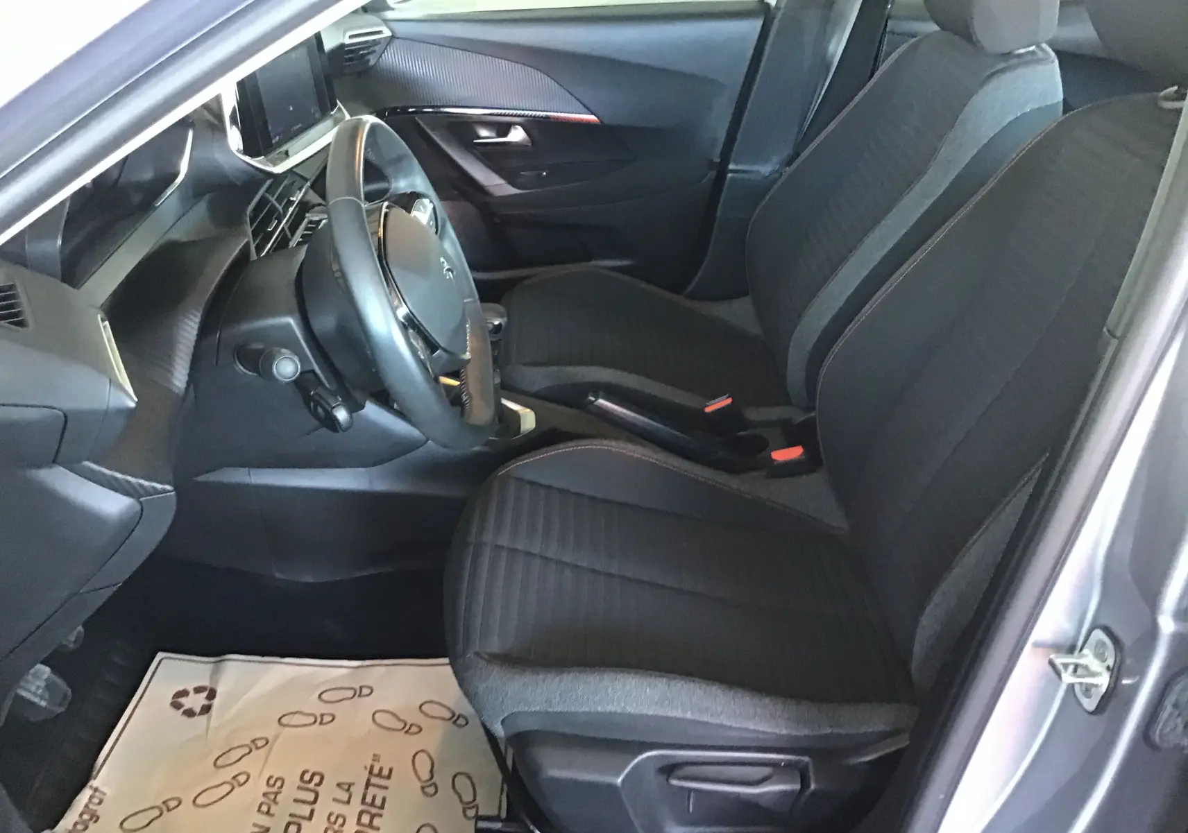 Vue intérieure côté conducteur du Peugeot 2008 gris Artense 2022, sièges tissu noir et tableau de bord moderne.
