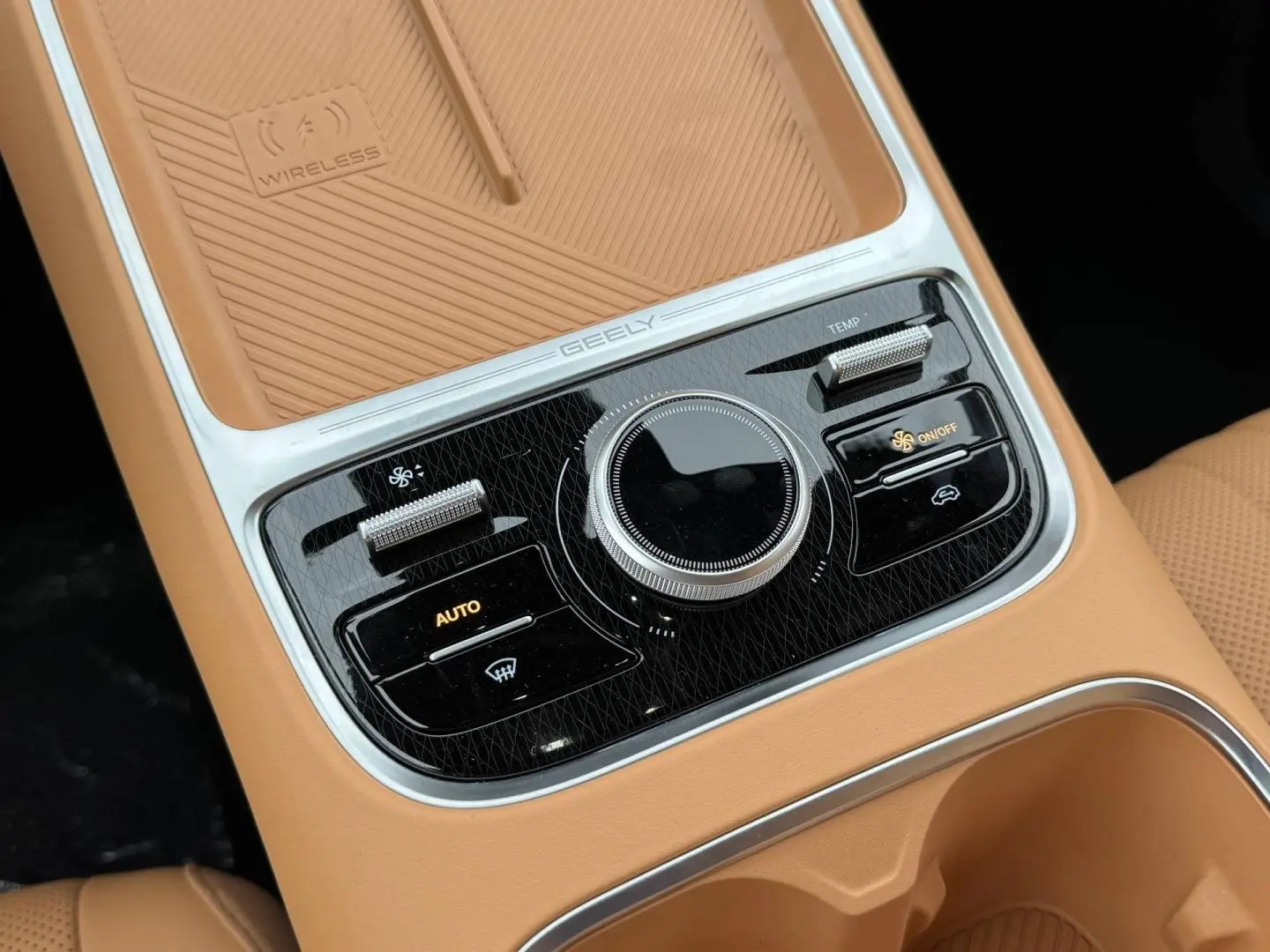 Gros plan sur la console centrale beige du Geely STARRAY 1.5 EM-i avec commandes climatiques et surface de recharge sans fil.