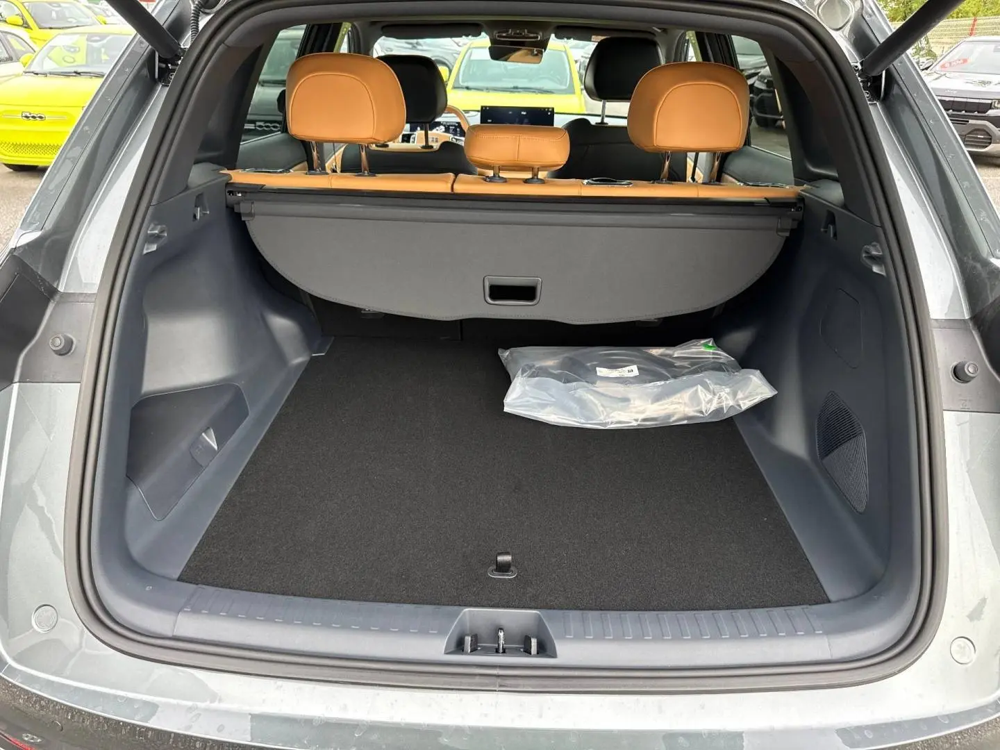 Coffre ouvert vu de l'arrière d'un Geely STARRAY gris volcanic avec banquette cuir camel et cache-bagages.