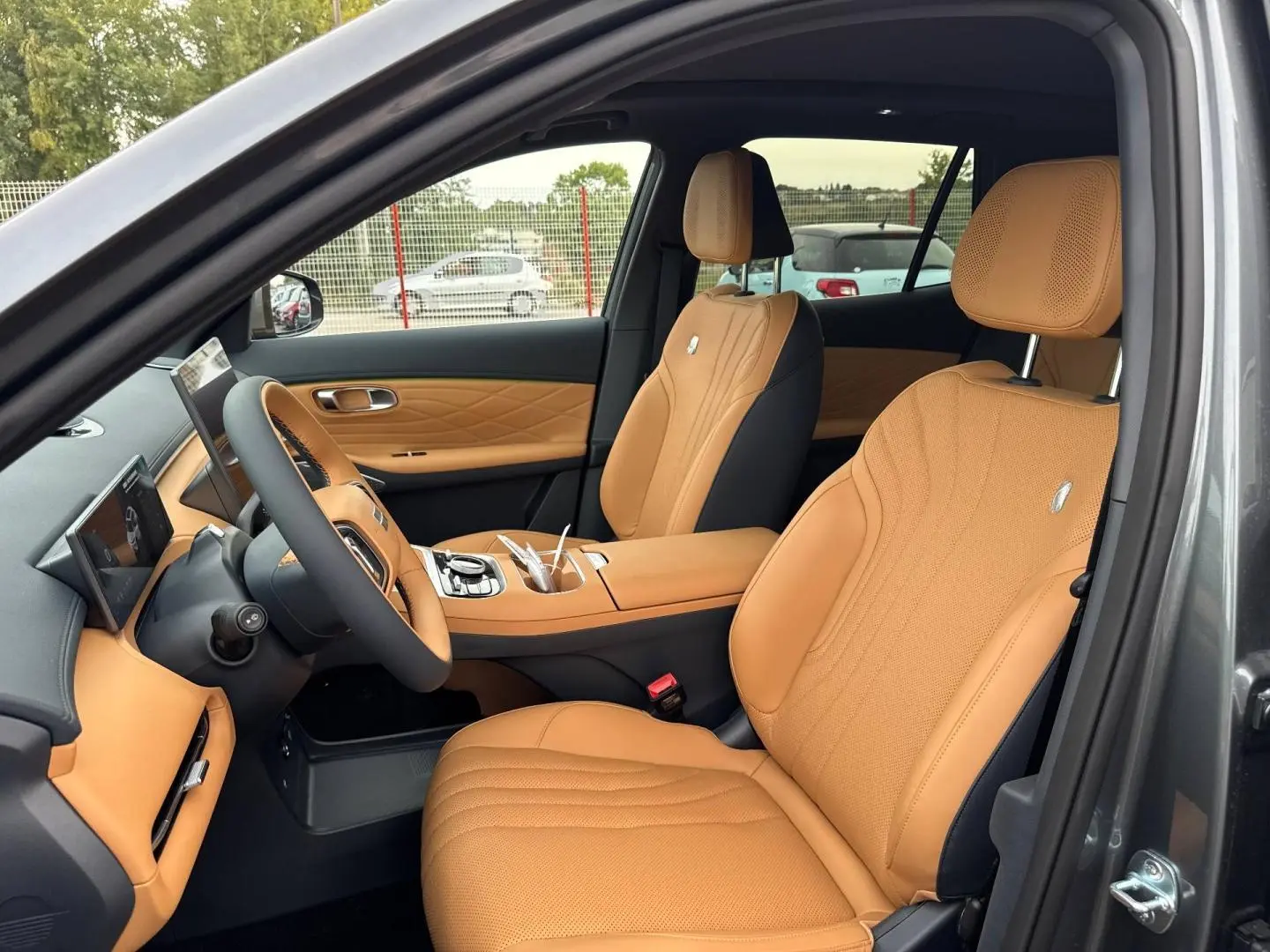 Vue intérieure côté conducteur du Geely STARRAY 1.5 EM-i 262ch Max+ en Volcanic Grey Metallic, sièges cuir camel élégants.