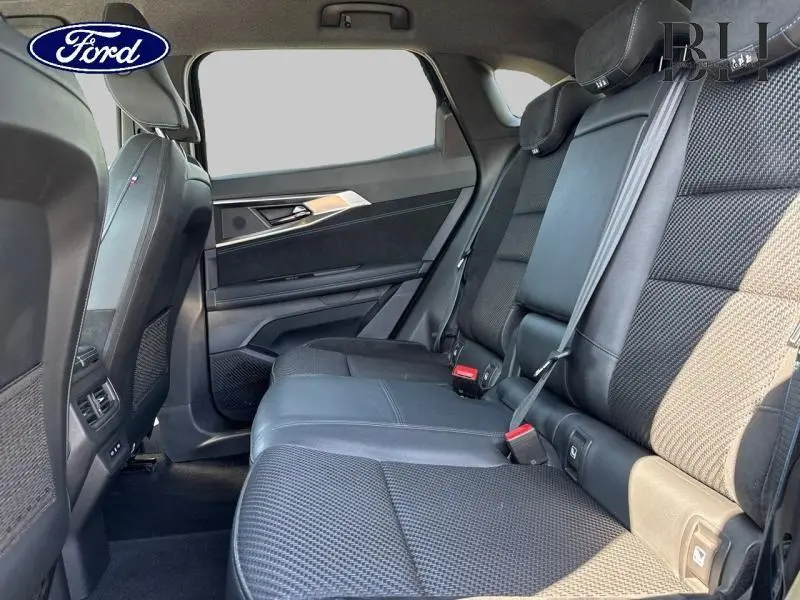 Vue intérieure côté droit des sièges arrière en tissu carbone et Alcantara du Renault Austral noir étoilé 2024 avec ceintures attachées.