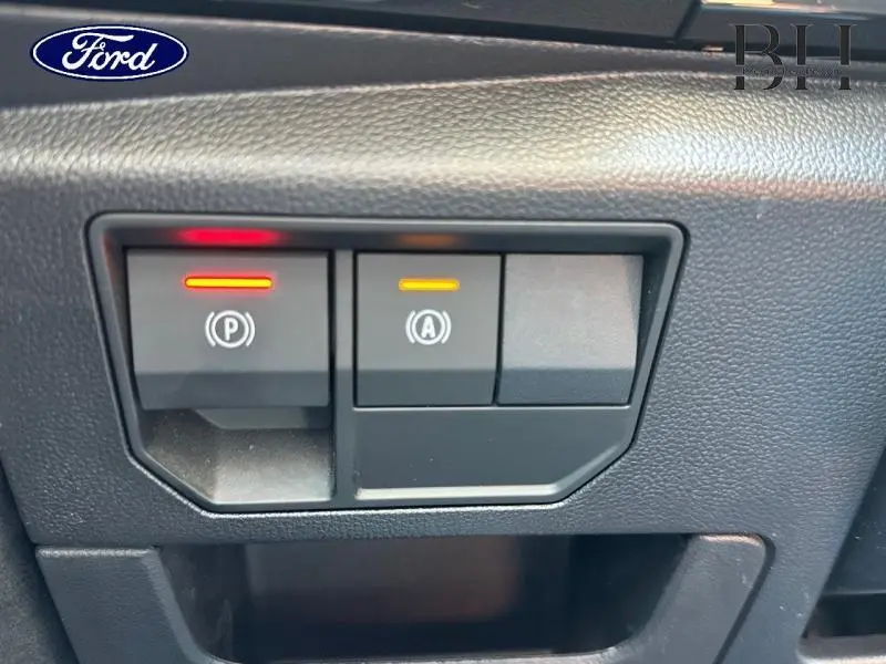 Gros plan sur les commandes électroniques de frein de stationnement et démarrage auto sur tableau de bord noir du Renault Austral 2024.