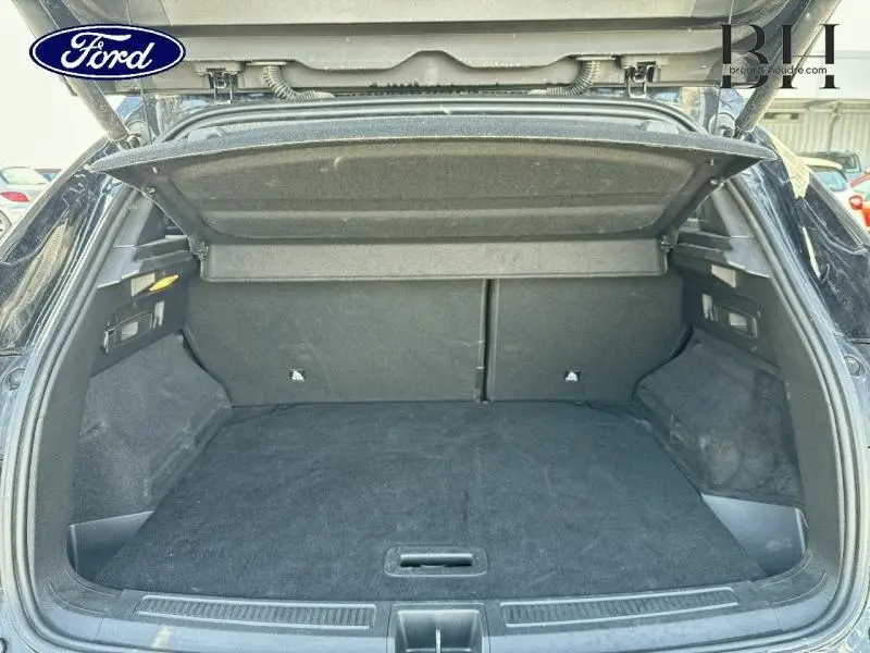 Coffre ouvert vu de l'arrière d'un Renault Austral noir étoilé avec hayon motorisé et intérieur spacieux.