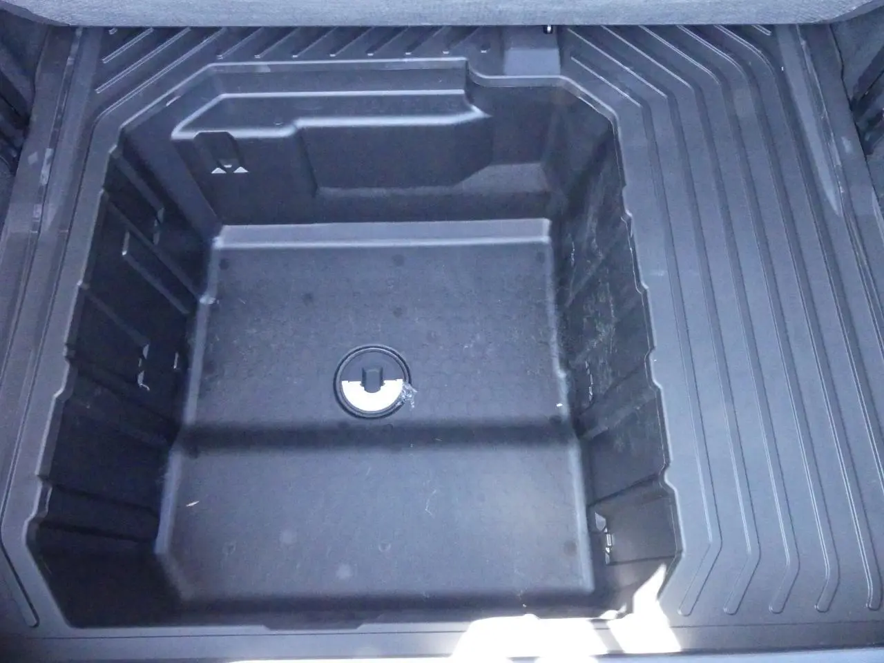 Vue plongeante sur le compartiment de rangement sous le plancher du coffre du Ford Puma gris métallisé 2025.