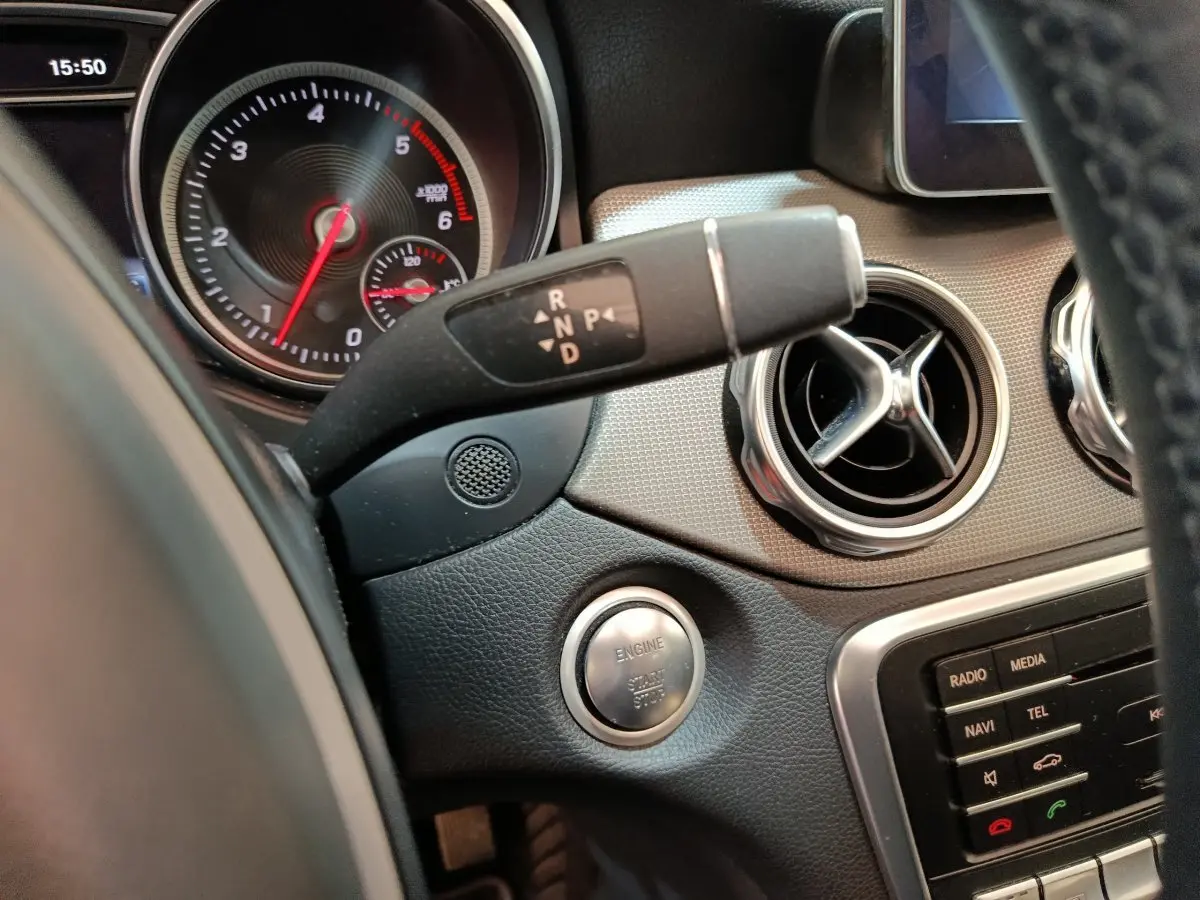 Détail intérieur du tableau de bord d'une Mercedes GLA 220 d noir, avec bouton démarrage et commandes de boîte auto visibles.