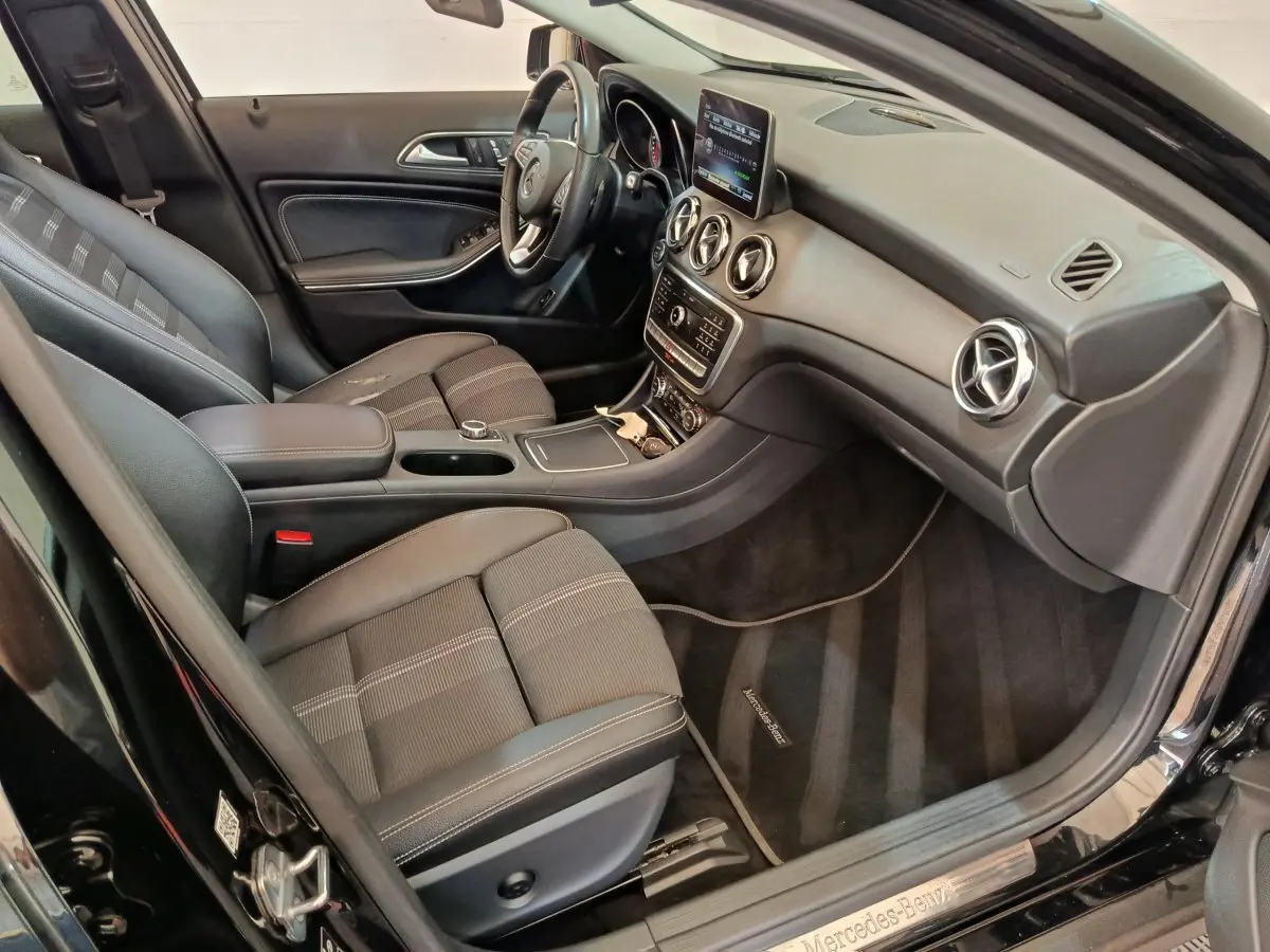 Vue intérieure côté conducteur du Mercedes GLA 220 d noir, avec tableau de bord moderne et sièges en tissu noir.