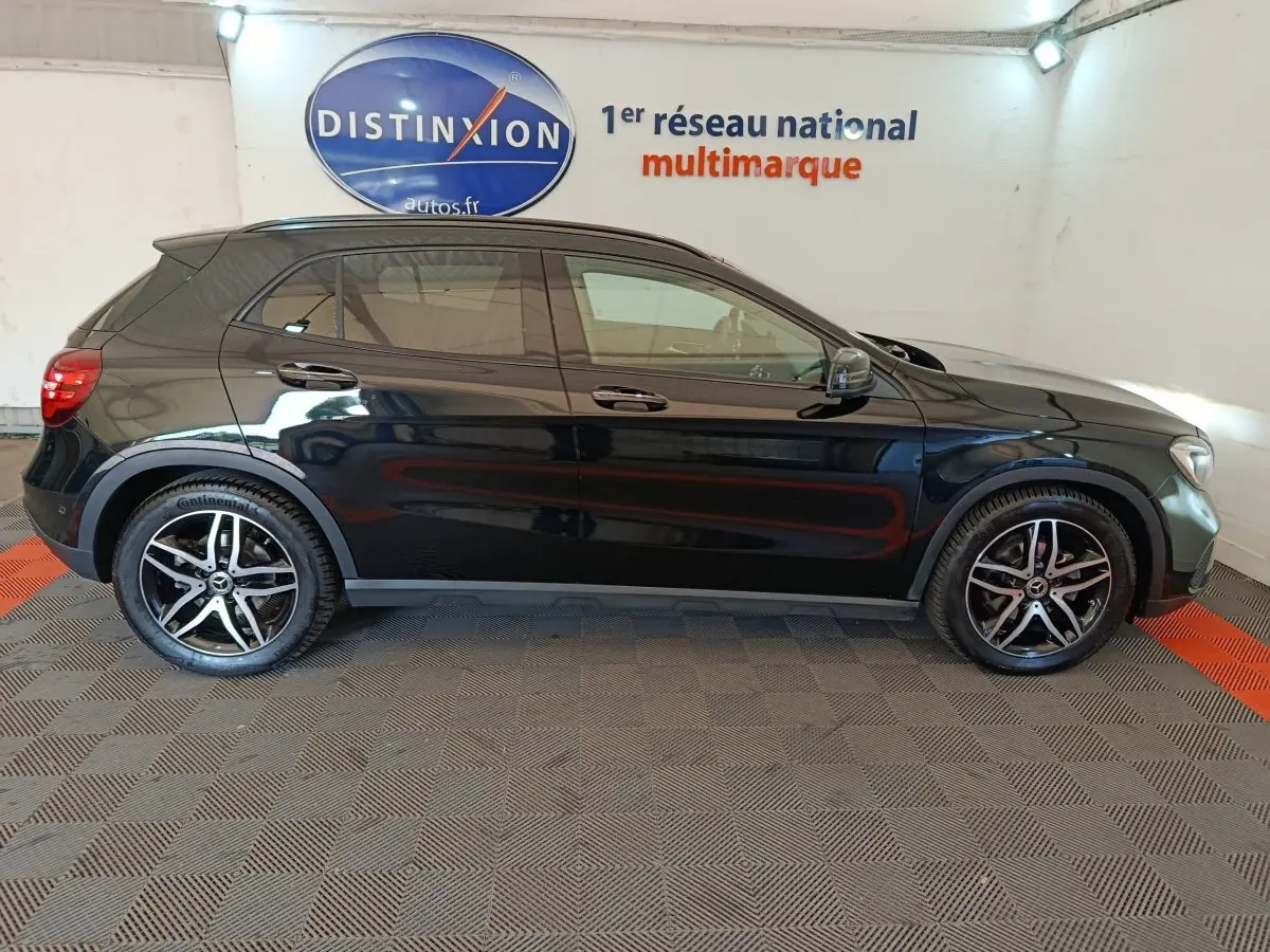 Mercedes GLA 220 d noir vue de profil côté gauche, avec jantes alliage et toit panoramique visible en intérieur showroom.