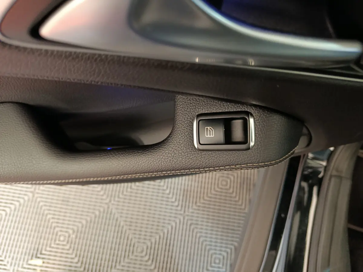 Bouton de commande de lève-vitre sur la porte côté gauche d'une Mercedes GLA 220 d noire, intérieur cuir noir.