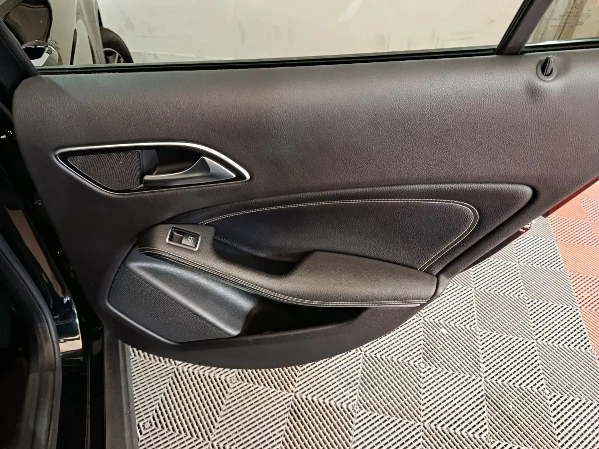 Porte intérieure côté gauche en cuir noir avec poignée argentée et bouton de commande de vitre, Mercedes GLA 220 d 2018.