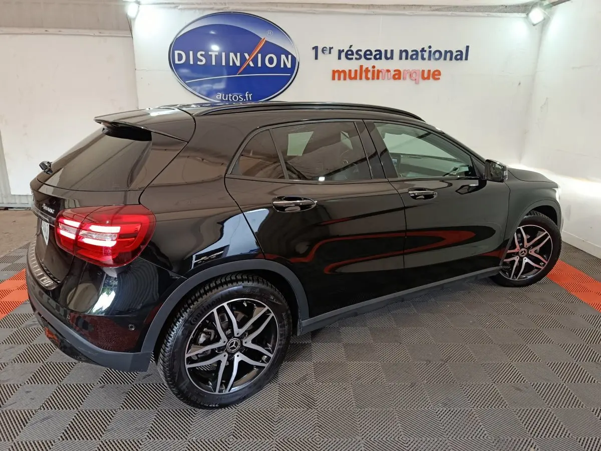 Mercedes GLA 220 d noir vue 3/4 arrière droit, avec jantes alliage et vitres teintées en intérieur showroom.