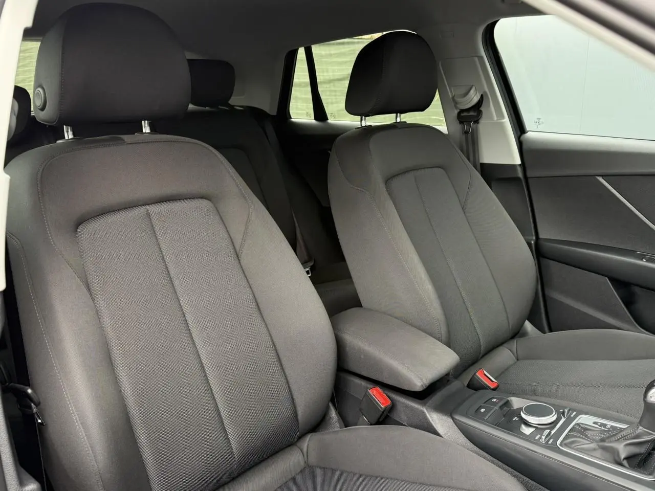 Vue intérieure des sièges avant noirs du SUV Audi Q2 35 TFSI S-Line 2023 avec console centrale et levier de vitesses.