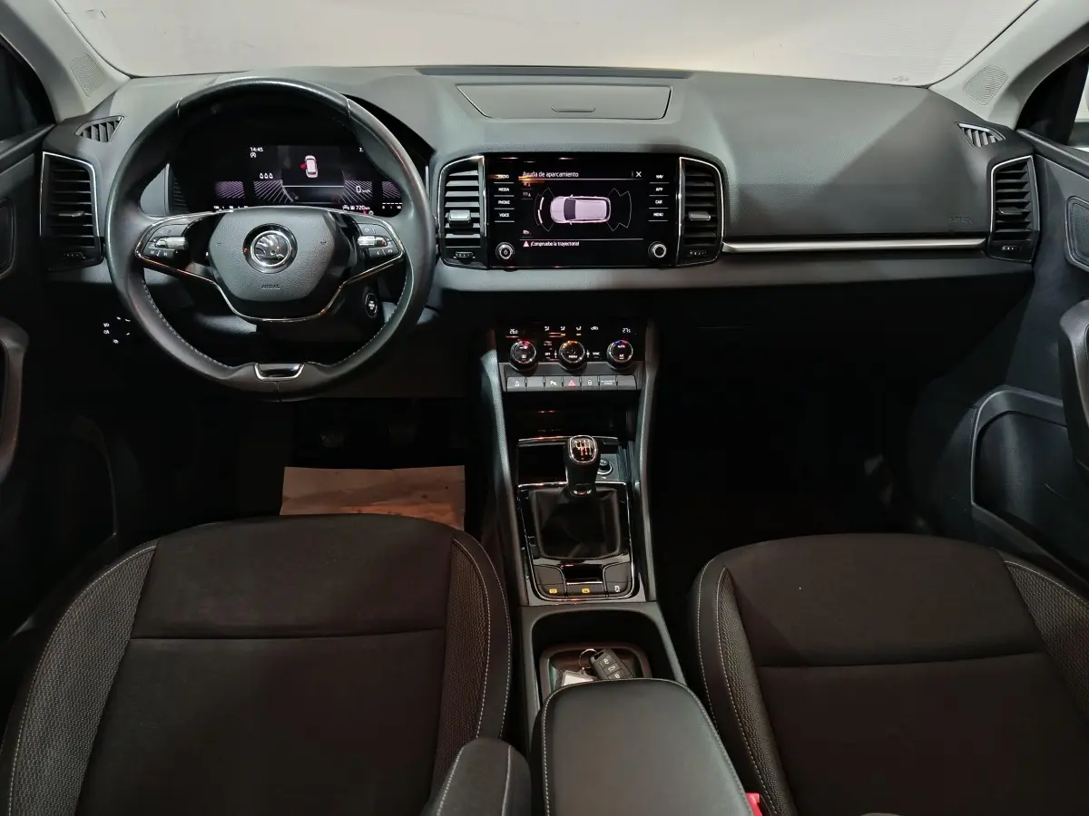 Intérieur noir du Skoda Karoq 2024, vue frontale du tableau de bord avec écran tactile et volant multifonctions.