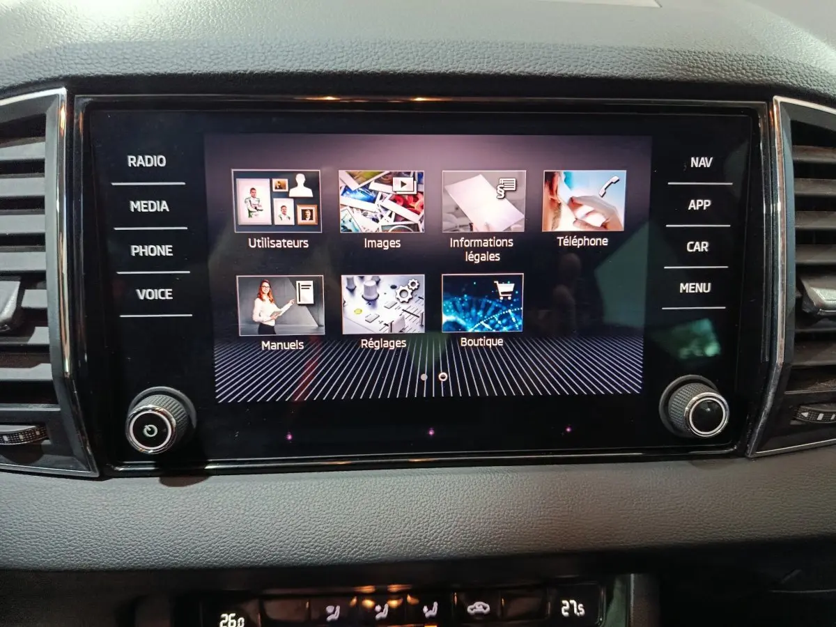 Écran tactile central allumé du tableau de bord gris du Skoda Karoq 2024, affichant menu multimédia et réglages.