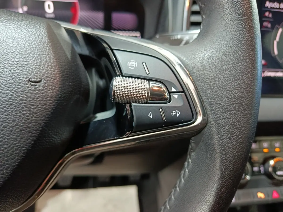 Gros plan sur les commandes multifonctions côté gauche du volant cuir noir du Skoda Karoq 2024.