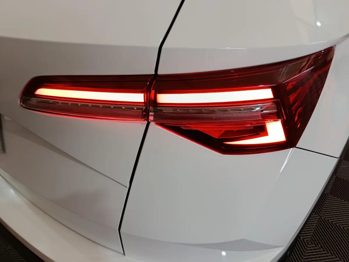 Feu arrière droit allumé d'un SKODA KAROQ blanc 2024, mettant en valeur son design LED moderne.