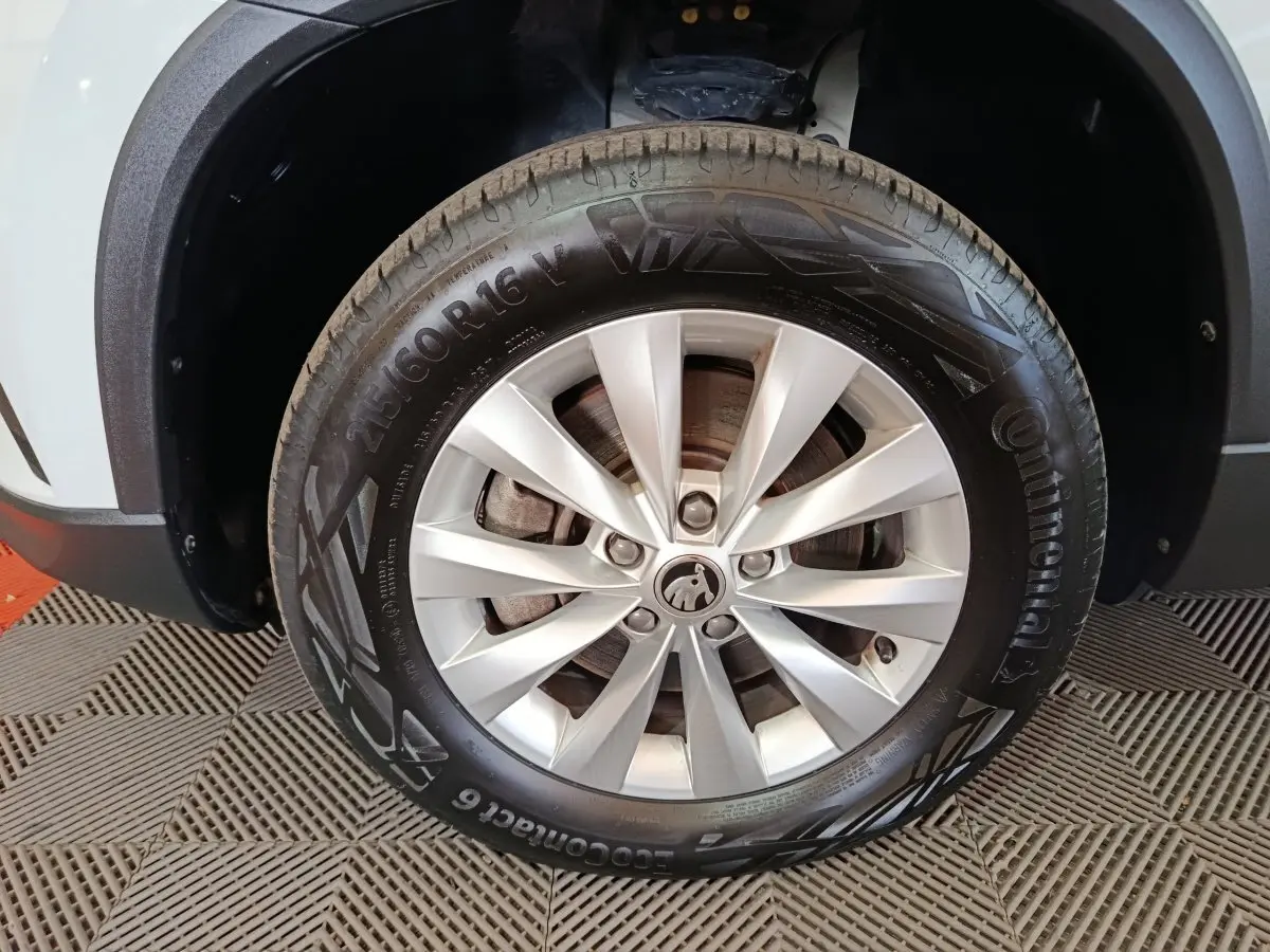 Gros plan sur la roue avant gauche argentée d'un Skoda Karoq 2024 avec carrosserie blanche visible en arrière-plan.